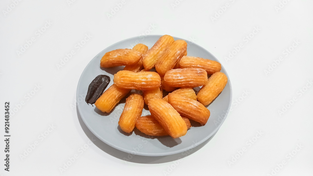 Churros sticks in a small plate with white powdered sugar and a bowl of chocolate sauce Churros sticks in a small plate with white powdered sugar and a bowl of chocolate sauce