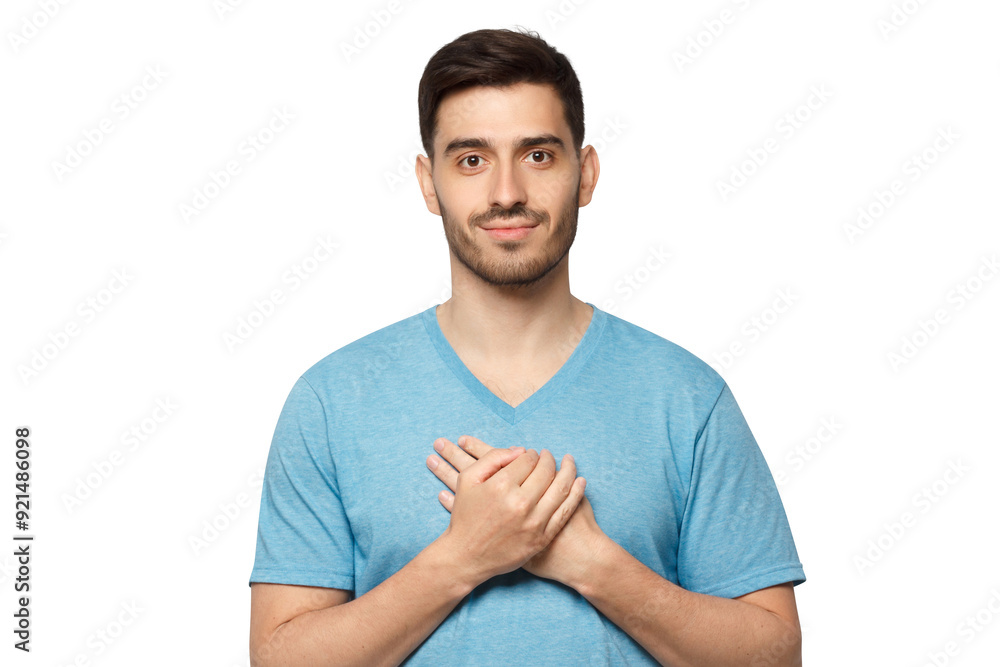 Fototapeta premium Kind hearted friendly nice guy shows kindness, wearing blue t-shirt. Smiling positive young man keeps hands on chest