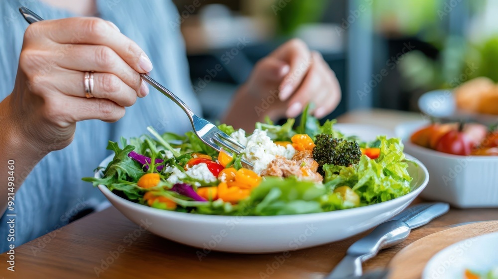 A person enjoys a fresh, vibrant salad topped with colorful vegetables, capturing the essence of healthy eating and well-being in a bright, natural setting. A person enjoys a fresh, vibrant salad topped with colorful vegetables, capturing the essence of healthy eating and well-being in a bright, natural setting.