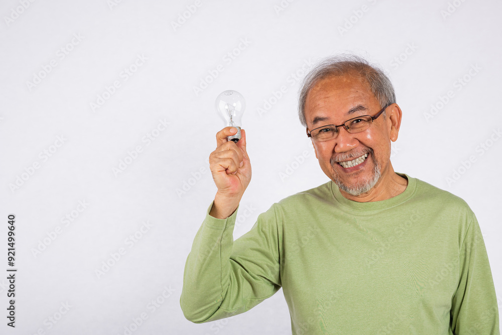 Portrait Asian old man is holding light bulb and smiling studio shot isolated on white background. Concept of intelligence and creativity, as the man is holding a symbol of innovation. Thinking idea Portrait Asian old man is holding light bulb and smiling studio shot isolated on white background. Concept of intelligence and creativity, as the man is holding a symbol of innovation. Thinking idea