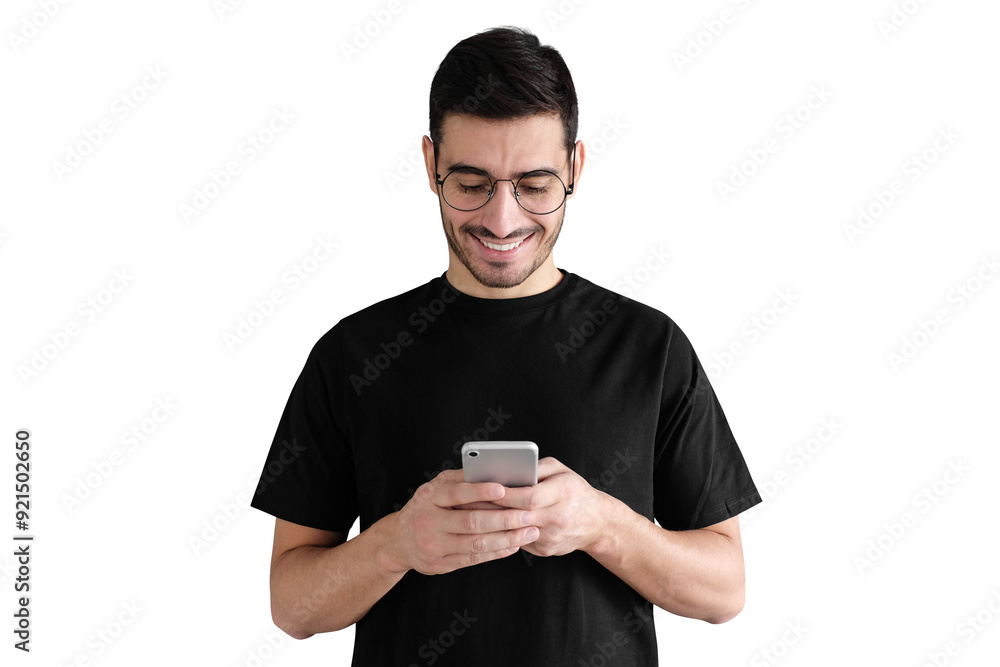 Young man standing against, looking at screen of phone, browsing web and smiling nicely while chatting Young man standing against, looking at screen of phone, browsing web and smiling nicely while chatting