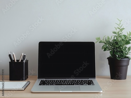 Neatly organized office desk with a laptop, notebook, and personal items