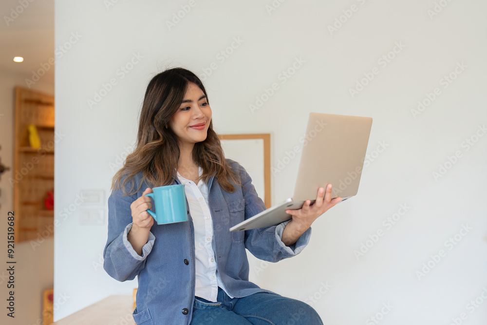 Young Woman Freelancer Working from Home with Laptop and Coffee Mug in Modern Home Office Setting Young Woman Freelancer Working from Home with Laptop and Coffee Mug in Modern Home Office Setting