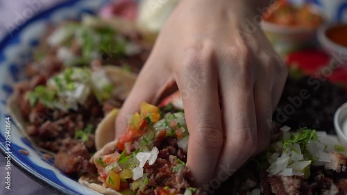 Mexican food beef pork taco hand picking salsa close up shot