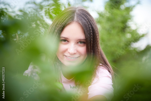 Portrait of young pretty woman with long brown hair in greenery