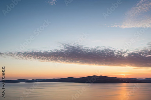 Sunset over calm water with mountain silhouette.