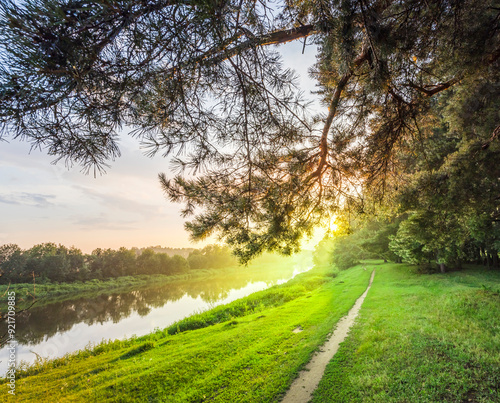 A tree branch is in the foreground of a beautiful, serene landscape