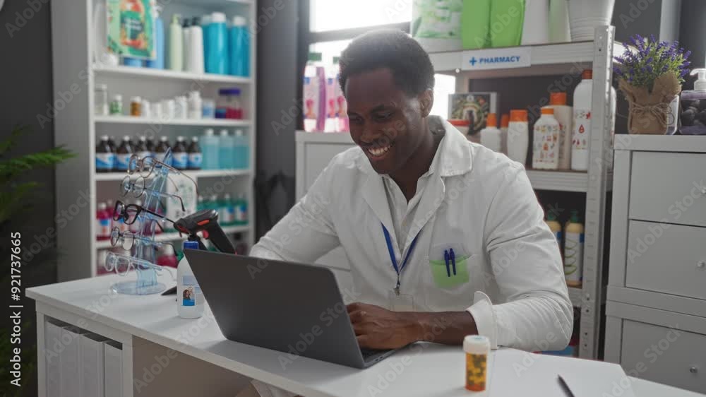 Young man working on laptop in pharmacy surrounded by various bottles and eyeglasses display Young man working on laptop in pharmacy surrounded by various bottles and eyeglasses display