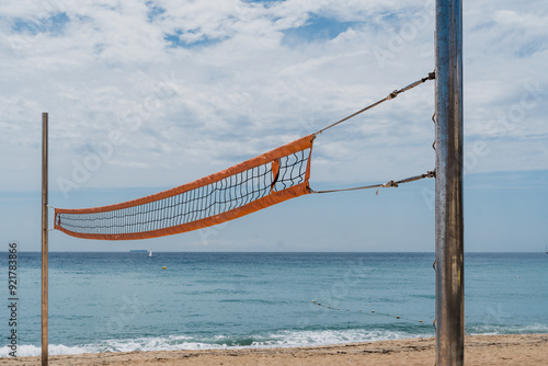 A weathered volleyball net stands before a calm ocean, symbolizing endurance and the passage of time. photo