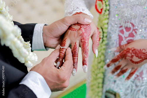 Bride and groom exchanging rings. Putting the ring on the bride's finger. Close-up photo of the hands of the Indonesian bride and groom. Indonesian wedding traditions