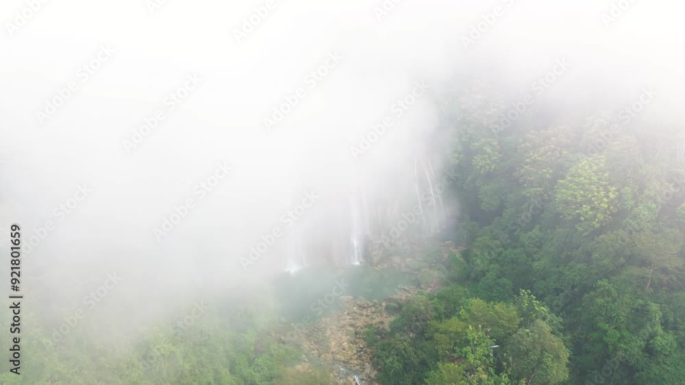 Aeriel view of waterfall between trees of high hills in a foggy day. Water flows down to rocky. Aeriel view of waterfall between trees of high hills in a foggy day. Water flows down to rocky.
