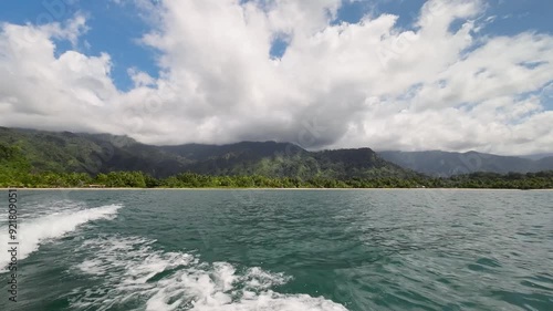 Tropical New Guinea coastline view from motorboat on sunny day with boat wake photo