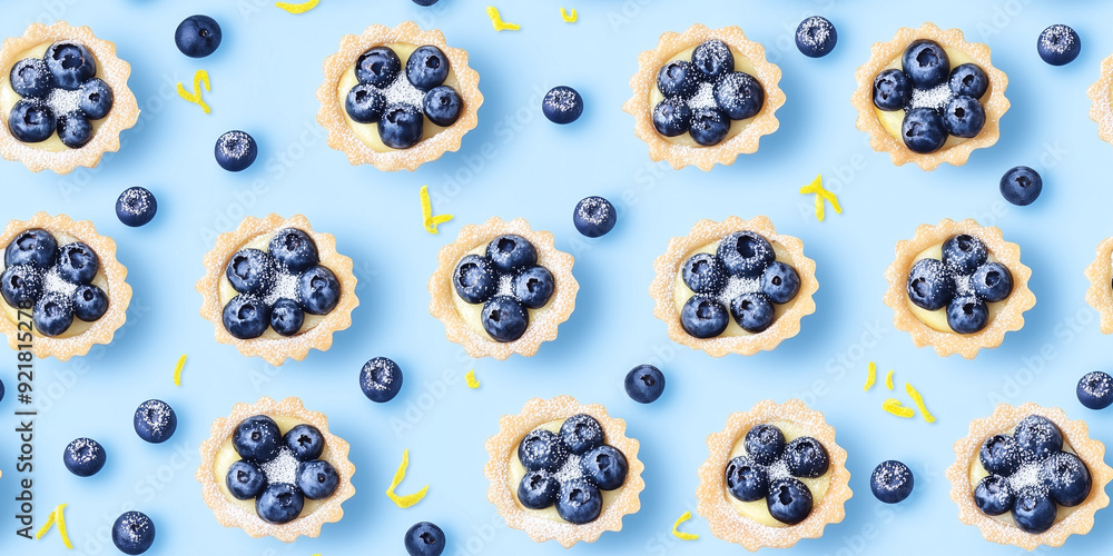 Blueberry tarts with lemon zest, powdered sugar, light blue background, seamless pattern Blueberry tarts with lemon zest, powdered sugar, light blue background, seamless pattern