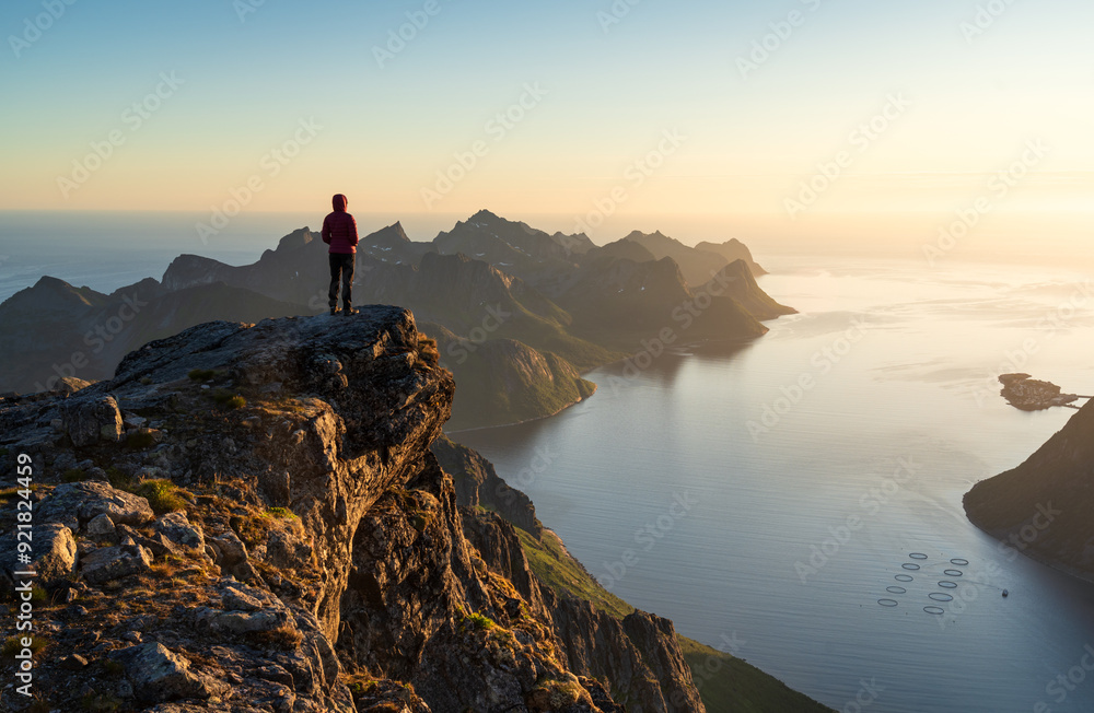 A woman enjoying the view and the midnightsun on the summit of Keipen, Senja.