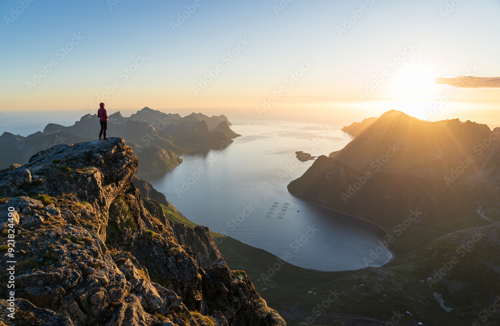 A woman enjoying the view and the midnightsun on the summit of Keipen, Senja.