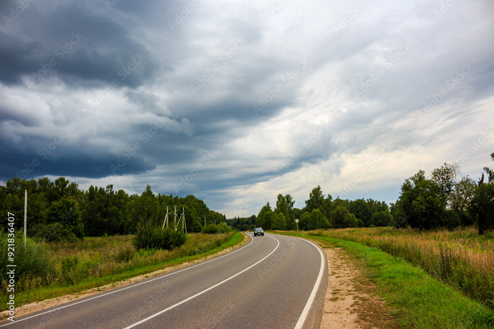 Menacing rain clouds moving towards the highway, landscape before the downpour Menacing rain clouds moving towards the highway, landscape before the downpour