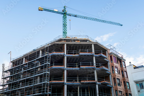 Wallpaper Mural View of a construction site featuring a green crane and the framework of a multi-story building under construction Torontodigital.ca