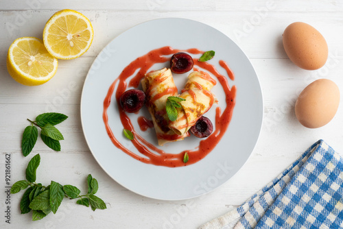 Delicious rolls with crepe dough filled with cherry sauce. Table decorated with Christmas decorations. photo