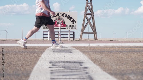 Man Walking Past Midpoint Sign Of Route 66 In Adrian, Texas. ground-level shot, slow motion