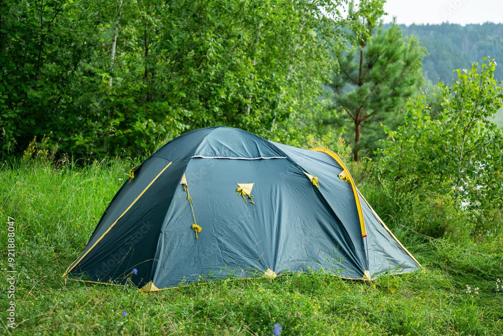 Green camping tent settled on the grass on top of the hill. Gloomy summer hiking day on nature, concept of tent as a main part of tourism equipment Green camping tent settled on the grass on top of the hill. Gloomy summer hiking day on nature, concept of tent as a main part of tourism equipment