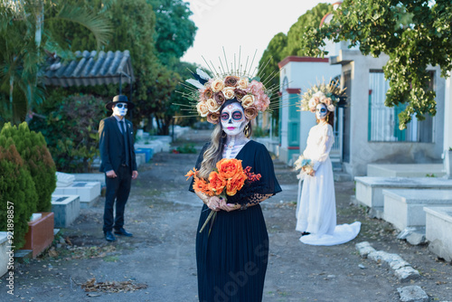 Group of three people made up as catrines in a cemetery. Day of the dead celebration. photo