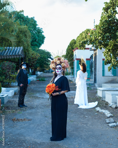 Group of three people made up as catrines in a cemetery. Day of the dead celebration. photo