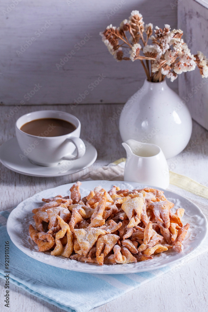 Traditional Maslenitsa dessert angel wings served with coffee on a light background.