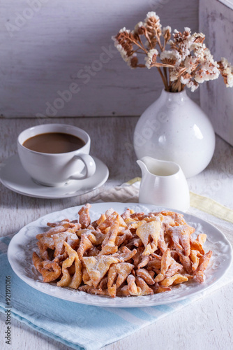 Traditional Maslenitsa dessert angel wings served with coffee on a light background.
