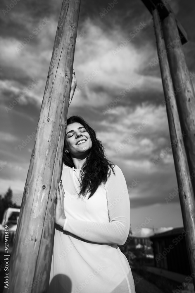 Fototapeta premium A woman in a white dress dances and poses on a swing high in the mountains at sunset. Freedom concept