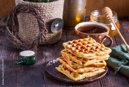 Obraz na płótnie Belgian waffles served with honey, cream and sai on a wooden background. Rustic style. w salonie