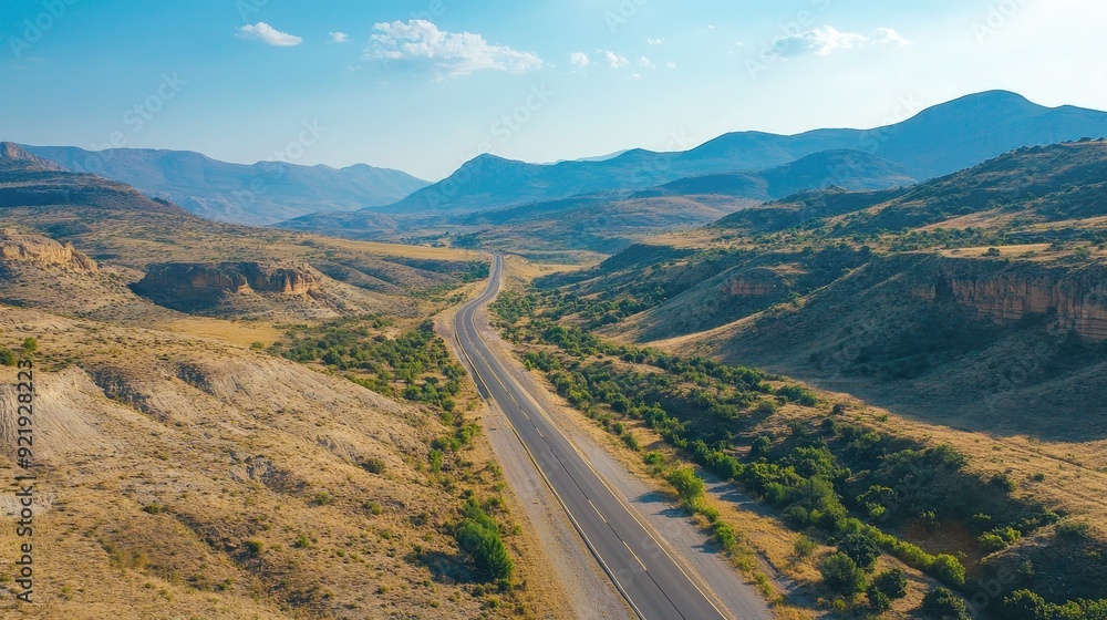 Aerial view of a picturesque road running parallel to a mountain range with clear skies. Perfect for landscape and travel conten Aerial view of a picturesque road running parallel to a mountain range with clear skies. Perfect for landscape and travel conten
