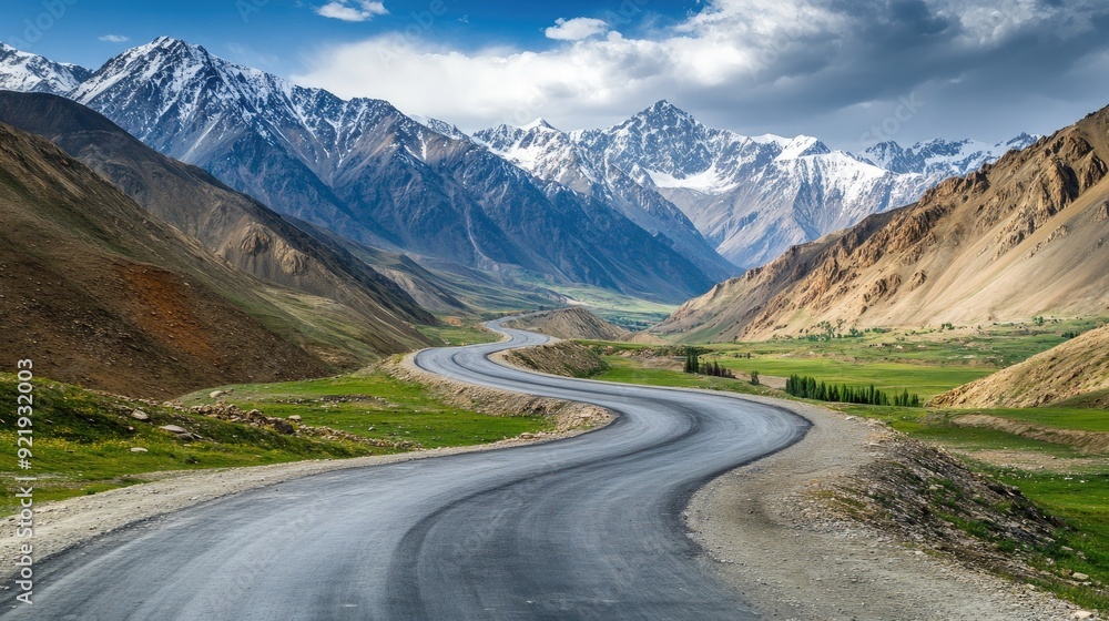 Fototapeta premium Scenic mountain road with sweeping curves and distant peaks surrounded by open space. Ideal for travel guides and exploration themes