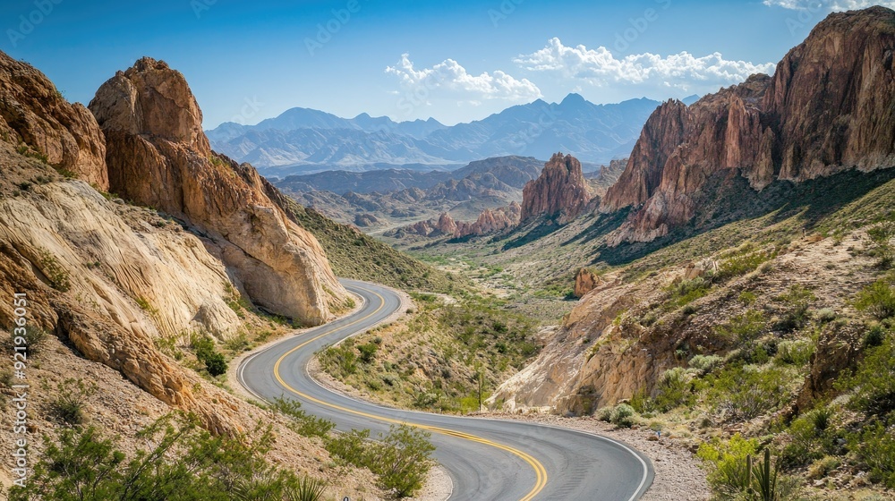 Top view of a winding road with a backdrop of towering mountains and clear skies. Ideal for road trip and adventure content Top view of a winding road with a backdrop of towering mountains and clear skies. Ideal for road trip and adventure content