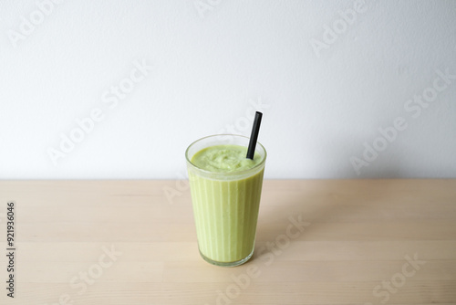 Healthy homemade avocado smoothie in a glass with a straw on a light background.