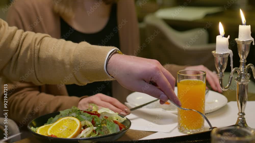 Young Male Hand Takes a Piece of Roast Meat with a Fork in front of a Young Woman at Dinner. Concept of fine dining, eating, appetite, indulgence, luxury, expensive, anniversary, food culture, hunger Young Male Hand Takes a Piece of Roast Meat with a Fork in front of a Young Woman at Dinner. Concept of fine dining, eating, appetite, indulgence, luxury, expensive, anniversary, food culture, hunger