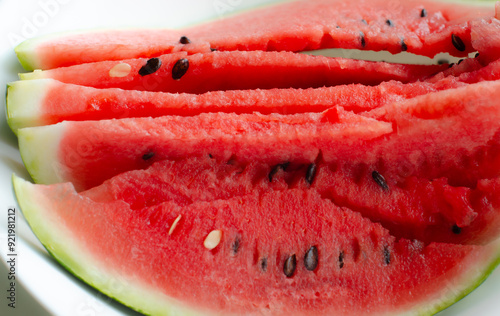 Fresh watermelon pieces arranged in an artistic pattern on a white plate.