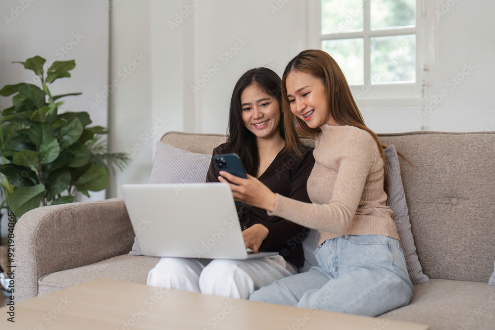 Happy Lesbian Couple Relaxing in Modern Living Room, Using Laptop and Smartphone, Enjoying Quality Time Together