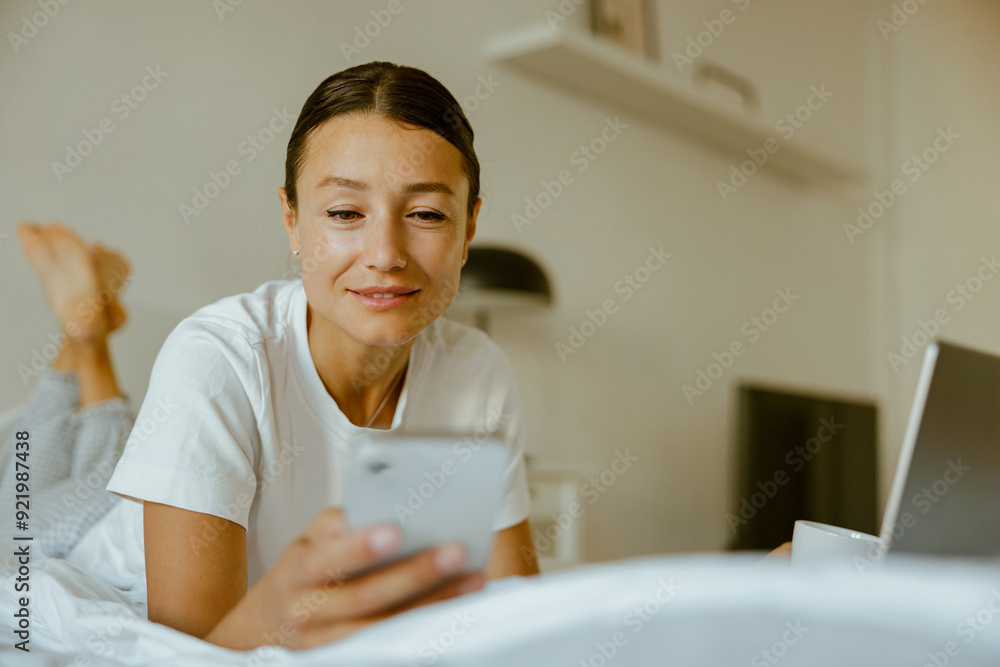 A Woman Comfortably Relaxing at Home While Using Her Mobile Phone and Laptop Alongside A Woman Comfortably Relaxing at Home While Using Her Mobile Phone and Laptop Alongside
