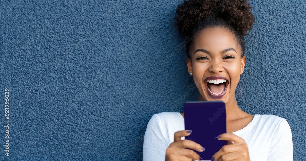 A joyful young African woman with short hair celebrates a delightful moment while excitedly checking her phone in a stylish studio setting A joyful young African woman with short hair celebrates a delightful moment while excitedly checking her phone in a stylish studio setting
