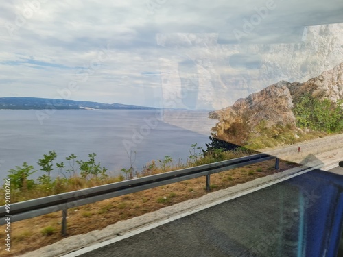 Scenic landscape of  mountains and sea on a cloudy summer day. People hurry up to vacation on of beautiful clean place by the Adriatic Sea. View of the coast of rocky island. Curve road in mountain.