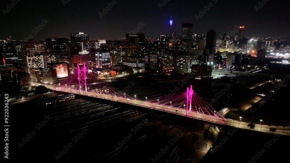 Obraz premium Nelson Mandela Bridge At Johannesburg In Gauteng South Africa. City At Night Landscape. Illuminated Cable Bridge. Johannesburg At Gauteng South Africa. Landmark Buildings. Colored Bridge.