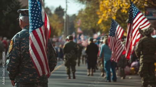 A group of people participating in a Veterans Day parade, carrying American flags, some dressed in military uniforms, and others in civilian clothes, showing respect and gratitude to those who served