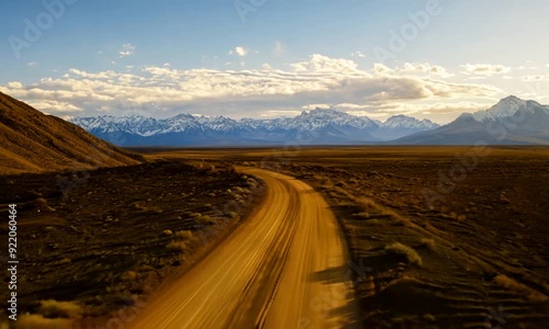 Stunning, sweeping landscape with a long, endless dirt road leading to mighty mountain peaks. photo