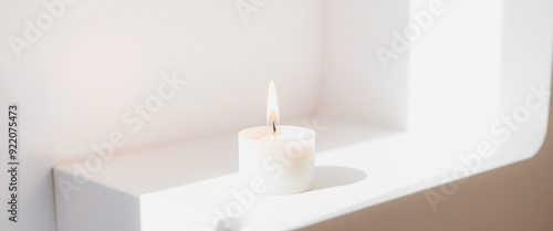 White Candle Burning on a White Shelf