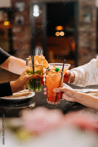 Cheers with colorful cocktails raised high, celebrating together at a vibrant gathering