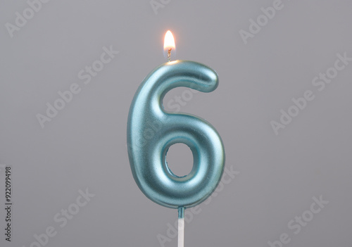 Canvas Print Burning blue birthday candle on gray background, number 6