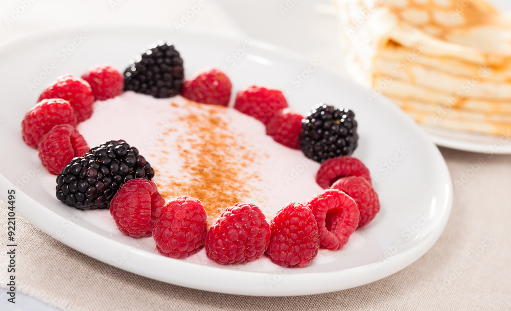 Breakfast of raspberries and blackberries with yogurt and pancakes on table Breakfast of raspberries and blackberries with yogurt and pancakes on table