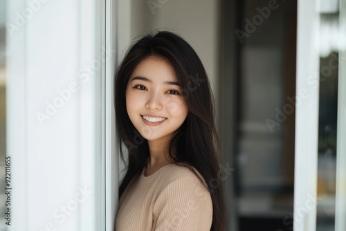 A young professional Asian woman in a gray suit, smiling as she gears up for a business meeting, highlights her potential and expertise.