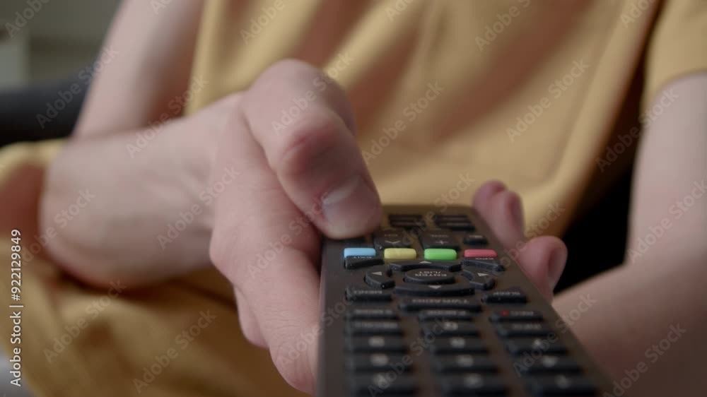 Closeup of hand of anonymous person pressing buttons on not working tv remote control, trying to switch channels indoors Closeup of hand of anonymous person pressing buttons on not working tv remote control, trying to switch channels indoors