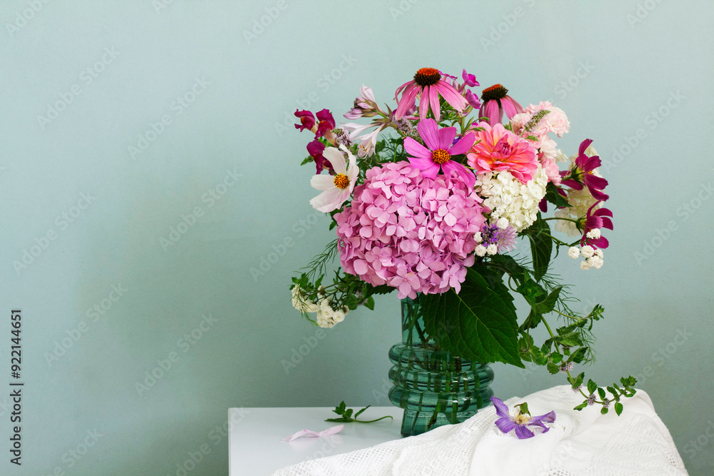 A bouquet of summer flowers in the room. Hydrangea, rose, echinacea, mint, snapdragon, asparagus and other flowers.
